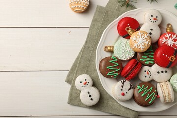 Beautifully decorated Christmas macarons on white wooden table, flat lay. Space for text