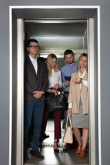 Group of office workers in modern elevator - obrazy, fototapety, plakaty