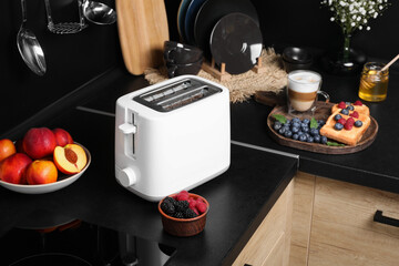 Fototapeta na wymiar Modern toaster, bread with fresh berries and coffee on countertop in kitchen