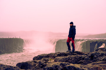 Obraz premium portrait of sporty man on rock among impressive waterfalls in the arctic polar circle in autumn winter