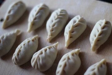 Fototapeta na wymiar dumplings with chopped meat traditional Russian cuisine. Close-up food knolling with flour on wooden board