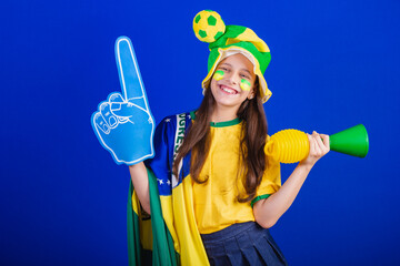 young girl, soccer fan from Brazil. dressed in hat and flag. using foam finger