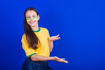 young girl, soccer fan from Brazil. presenting something with their hands.