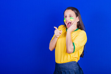 young girl, soccer fan from Brazil. startled, surprised, surprised. pointing something.