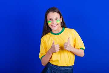 young girl, soccer fan from Brazil. thumb up, positive, like.