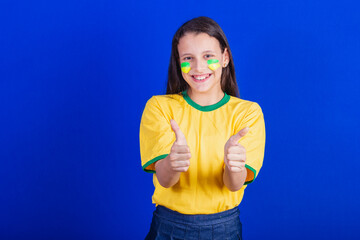 young girl, soccer fan from Brazil. thumb up, positive, like.