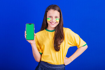young girl, soccer fan from Brazil. holding cellphone, screen for advertisement, promotion....