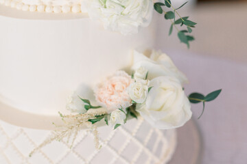 Close-up of a wedding cake, decorated with roses and greenery