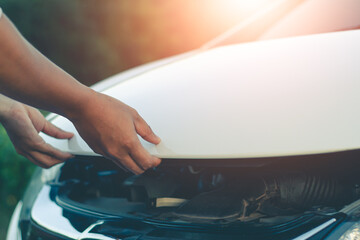 Woman inspects the damage of a damaged car on the road.