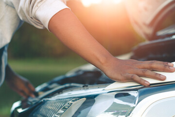 Woman inspects the damage of a damaged car on the road.