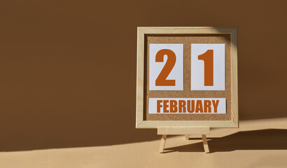 February 21th. Day 21 of month, Calendar date. Cork board, easel in sunlight on desktop. Close-up, brown background. Winter month, day of year concept