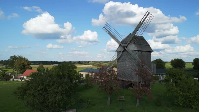 Clouds, shadow wind. Marvelous aerial view flight raise up drone
of a old Wooden Trestle windmill in brandenburg Germany at summer golden hour 2022. 4k marnitz Cinematic