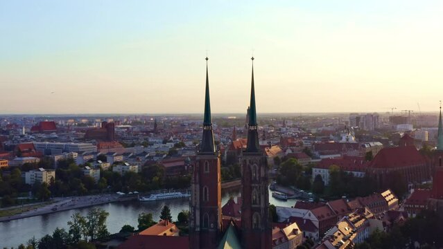4k aerial footage flying around the towers St John the Baptist cathedral view, the Oder River and town Wroclaw in sunset warm light City in western Poland with a lot of gothic architecture Summer