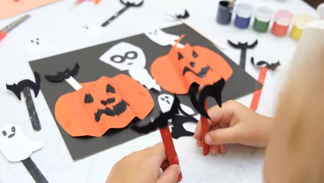 Child making pumpkins for the holiday of halloween. Funny crafts from paper. Halloween decor. Handicraft. The concept for Halloween. DIY. Children's art project, a craft for children.