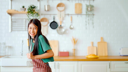 Asian young woman dancing in kitchen room. Female happy and relaxing at free time on weekend
