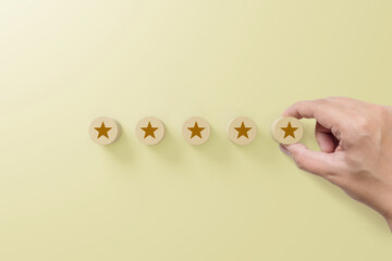 Hand putting wood block with five star symbol to increase rating of company with yellow background