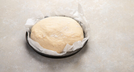 Raw dough pastry in a bowl on neutral background.