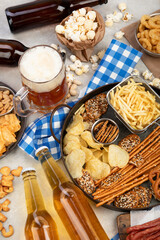 Assortment of beer and salty snacks on light background.