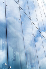 reflections of a cloudy sky in glass wall of an office building. abstract background.