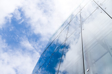 Fototapeta na wymiar modern glass office building reflecting cloudy sky. contemporary urban architecture.