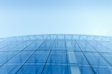 Fototapeta na wymiar transparent glass wall of office building against clear blue sky. abstract urban background.
