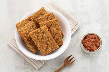 Tempeh, Tempe Goreng or Fried tempeh is Indonesia traditional food, made from fermented soybean seeds. Served with sambal (chilli sauce)
