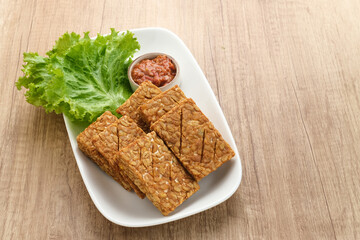 Tempeh, Tempe Goreng or Fried tempeh is Indonesia traditional food, made from fermented soybean seeds. Served with sambal (chilli sauce)

