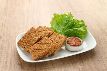 Tempeh, Tempe Goreng or Fried tempeh is Indonesia traditional food, made from fermented soybean seeds. Served with sambal (chilli sauce)
