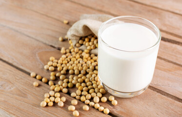 Soy milk in a glass with soybeans on a wooden table organic drink high protein healthy breakfast agricultural produce vegetarian - top view