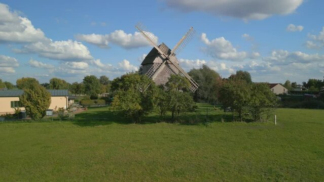 At eye level with the object. Unbelievable aerial view flight panorama orbit drone
of a old Wooden Trestle windmill in brandenburg Germany at summer golden hour 2022. 4k marnitz Cinematic