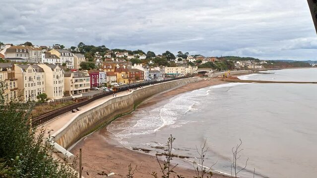 Beautiful zoom out of Dawlish seafront on a calm cloudy day as a train passes on the Exeter to Paignton English Riviera Line