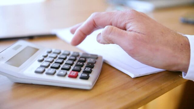 A person's hand typing into a calculator.