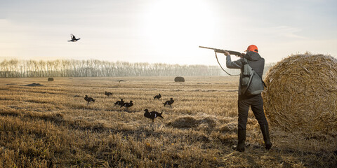 Hunter man with a gun during the hunt of wild birds or game. Hunting banner.