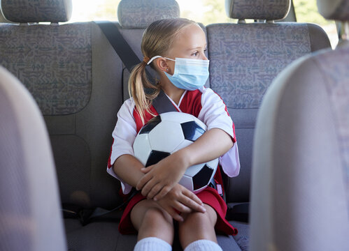 Covid, soccer and girl in a car to travel in backseat to a youth football training game for exercise and training. Face mask, coronavirus and young child in traffic traveling to a kids sports match