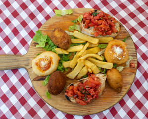 Traditional Italian food. Mix of mini fried pizza, breaded mozzarella, bruschette with tomatoes,...