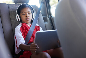 Sports, car travel and relax child with tablet on journey to soccer practice while streaming video,...