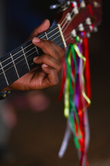 The hand of a pilgrim playing religious hymns on a decorated guitar during the Festa do Divino Espírito Santo religious celebrations, Remanso, Beni Department, Bolivia, on the border with Brazil