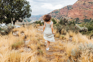 A young girl walks among the red high mountains. A girl walks in autumn among the beautiful mountains of Utah,USA
