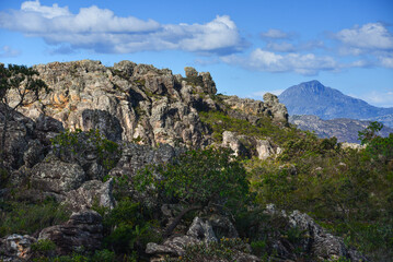 Fototapeta na wymiar Rugged rock formations and the Pico do Itambé mountain (2.002m), one of the highest on the Serra do Espinhaço range, as seen from the road between Milho Verde and Diamantina, Minas Gerais, Brazil