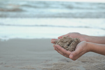 Close-up hand holding wet sand. Sand. Summer beach holiday vacation concept. A joyful time, happy by the beach with copy space. Environmental saving and  conservation background concept.