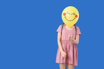 Young woman holding balloon with drawn smile on blue background with space for text