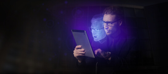 Young businessman with tablet computer and his digital projection on dark background. Concept of...