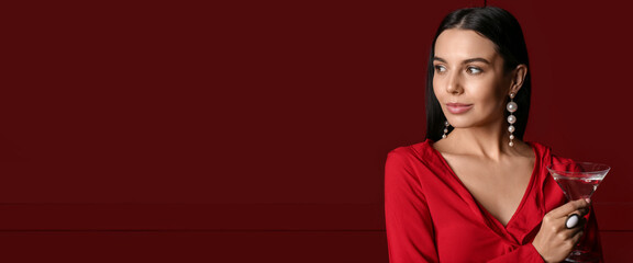 Beautiful young woman drinking martini on dark red background with space for text