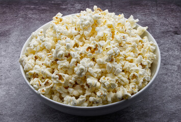 Bowl of fresh popcorn isolated on grey concrete background.