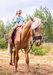 Outside on a beautiful warm day, a girl rides a horse.