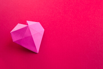 Pink paper heart origami isolated on a red background