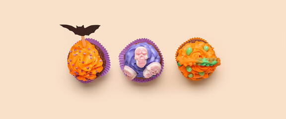 Tasty Halloween cupcakes on beige background, top view