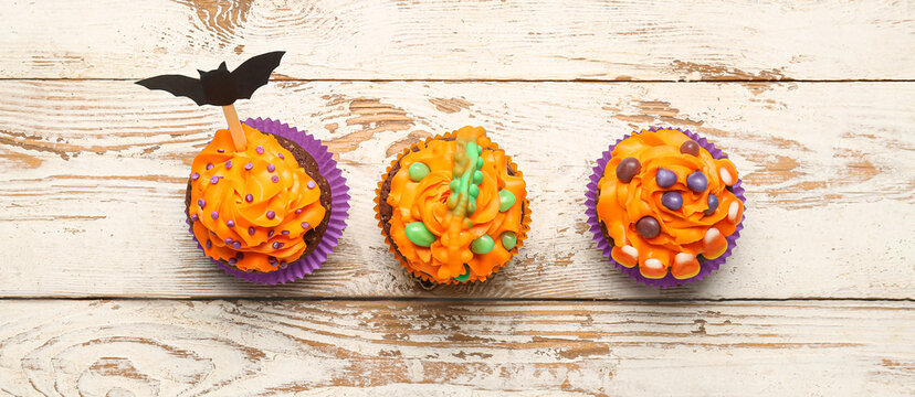 Tasty Halloween Cupcakes On Light Wooden Background, Top View