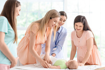 Female speaker teaching expectant mothers how to swaddle baby at course