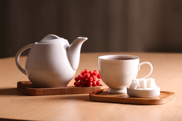 Teapot with hot beverage and cup of tea on table in cafe